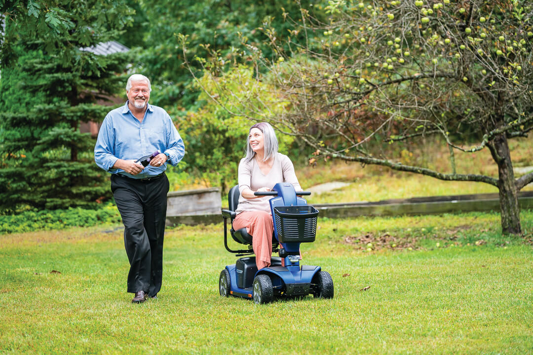 couple enjoying time outside in the grass; one using powered mobility